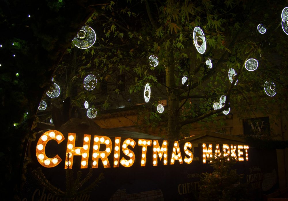 An illuminated sign of Christmas Market with silver baubles.