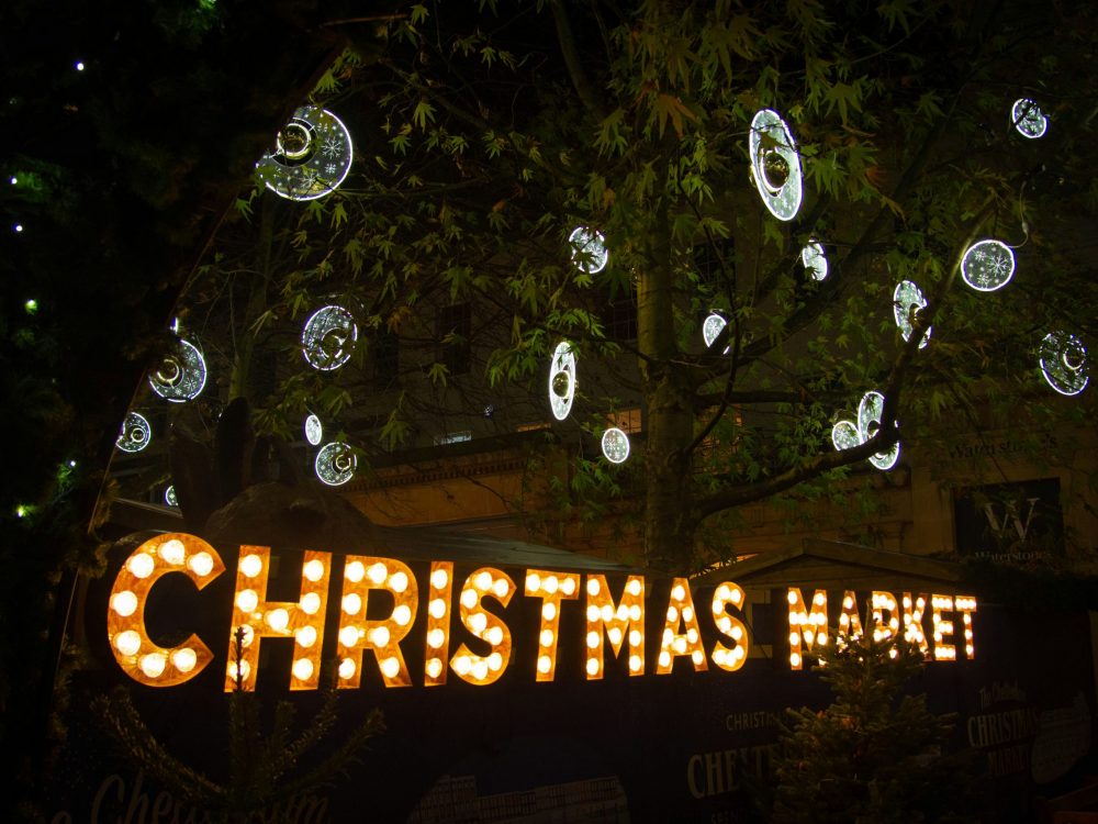 An illuminated sign of Christmas Market with silver baubles.