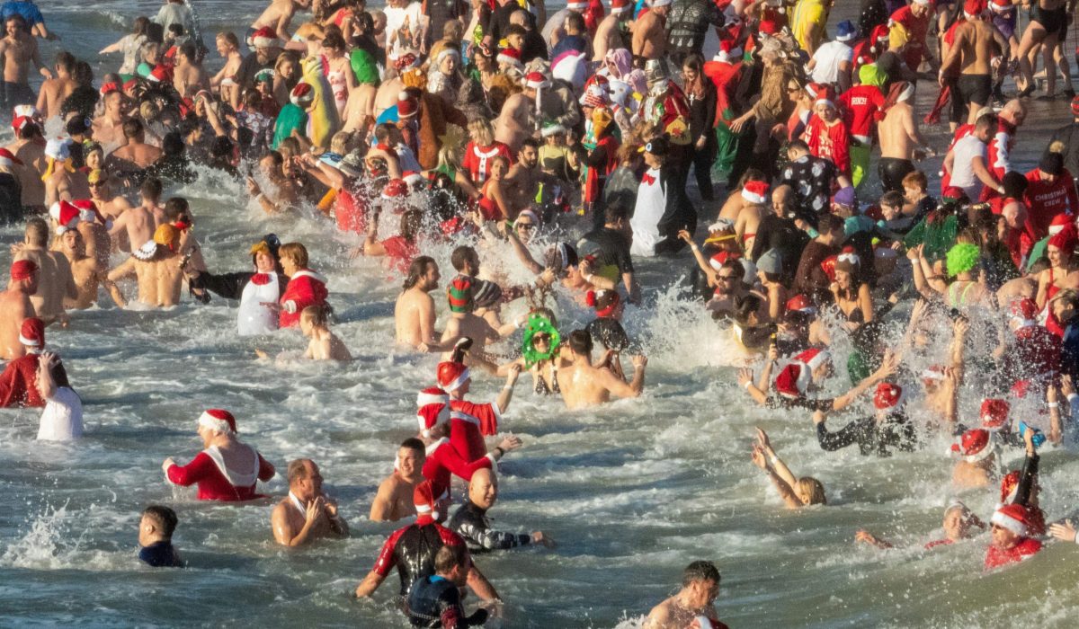 swimmers, some with christmas hats, costumes in the sea.