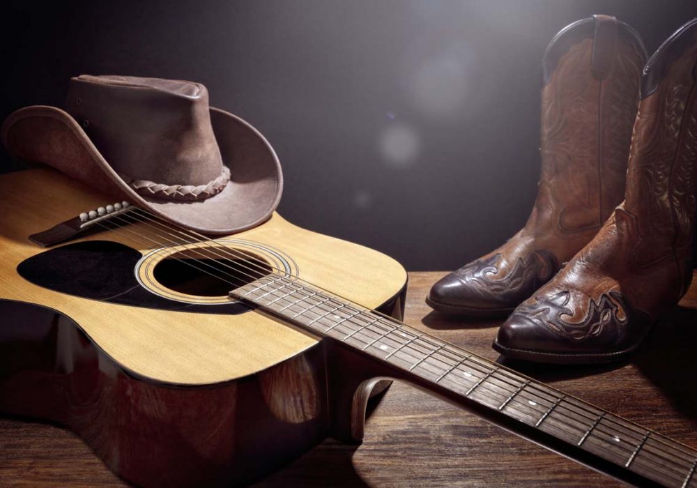 Country music festival live concert with acoustic guitar, cowboy hat and boots background