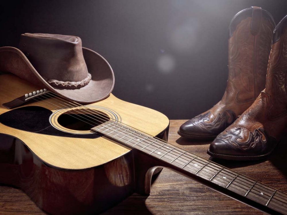 Country music festival live concert with acoustic guitar, cowboy hat and boots background